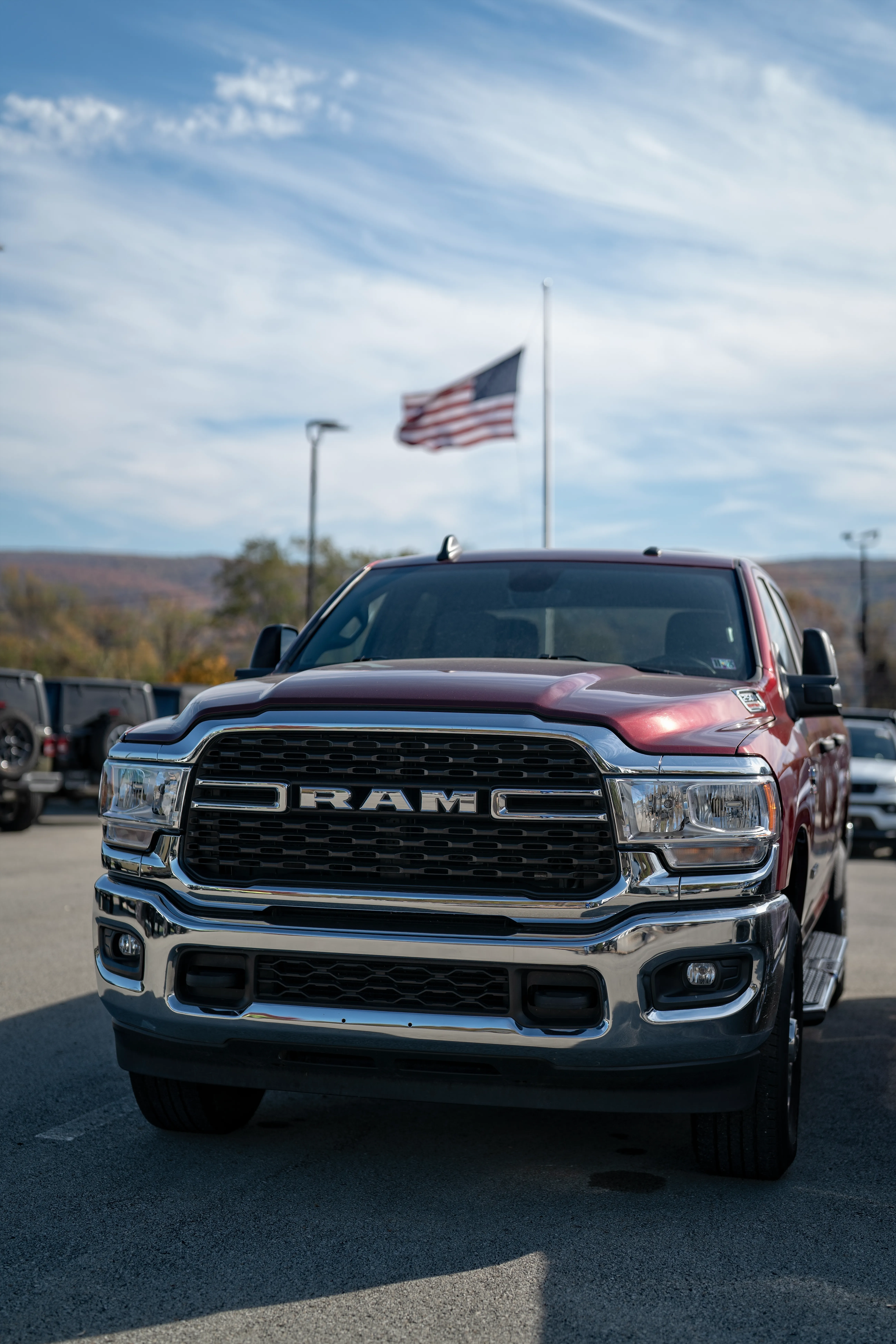 Red Ram truck at C. Harper CDJR with an American flag flying in the background